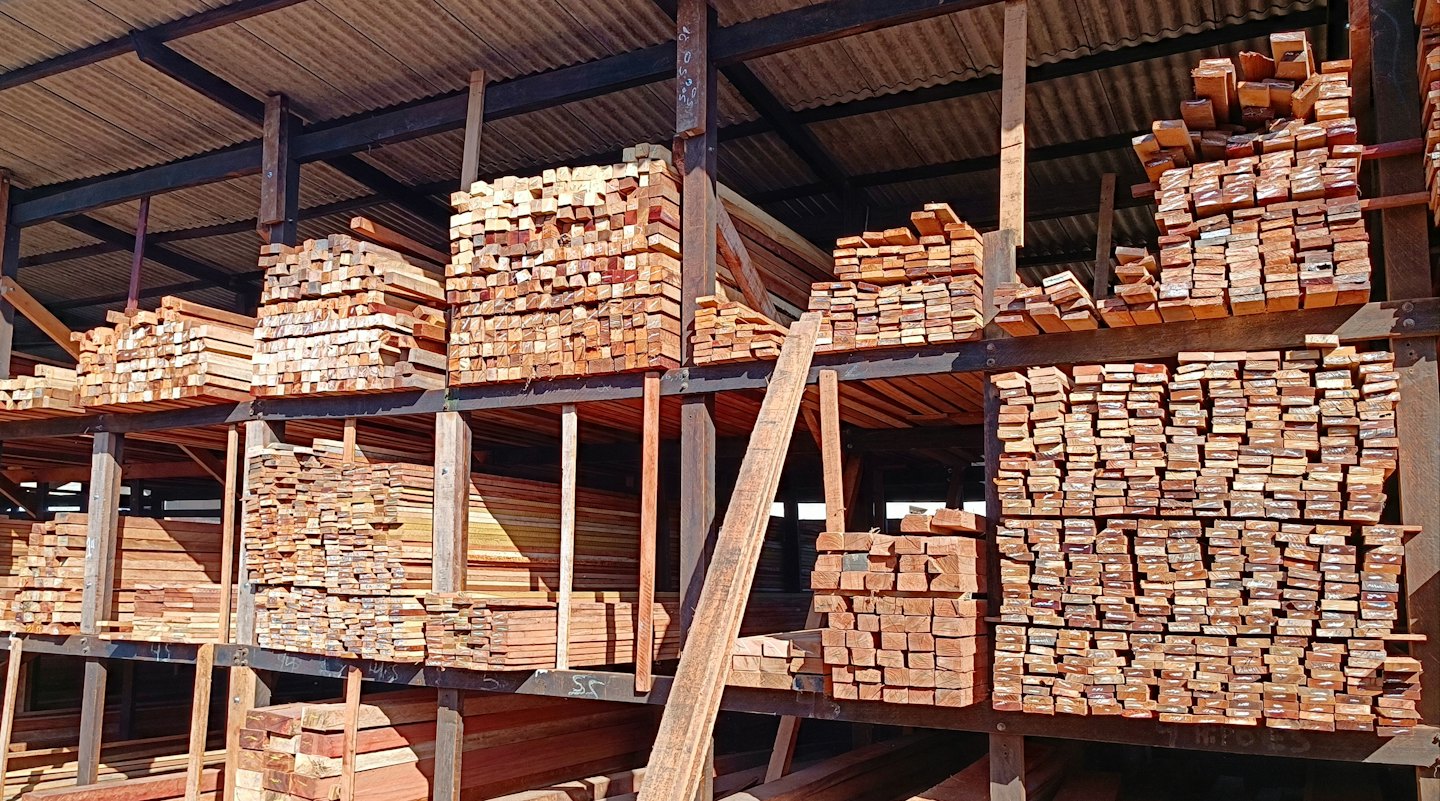 Tablones de madera cortada apilados en estanterías de almacén industrial.