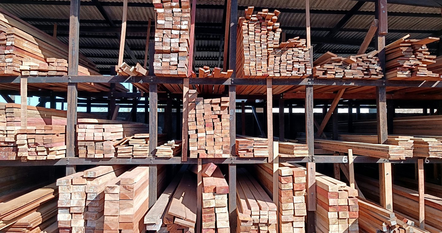 Tablones de madera apilados llenan los estantes de un depósito de madera organizado.